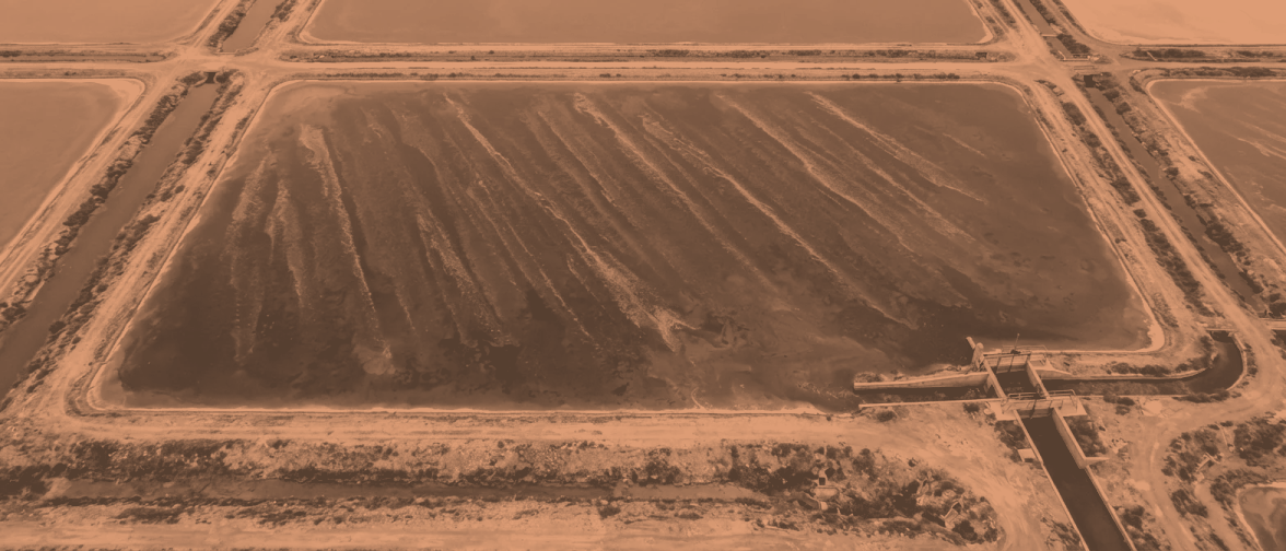 Pan 5 from 300 metres: one concentrating brine pan, the water dense and opaque and streaked in long wind lanes, hard geometric banks on every side.